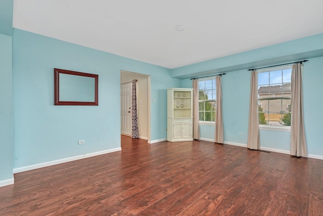 empty room featuring dark wood-type flooring and baseboards