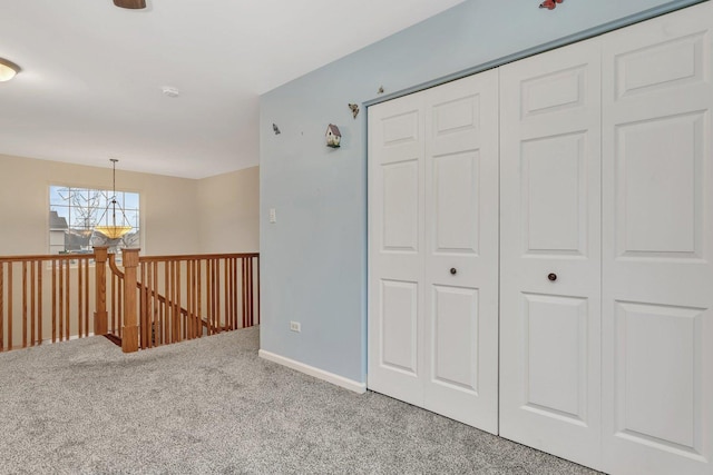 interior space featuring carpet floors, baseboards, and an upstairs landing