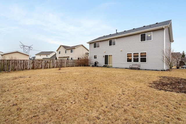 rear view of house with a lawn and fence