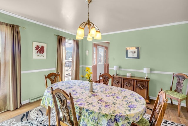 dining space featuring crown molding, an inviting chandelier, a baseboard heating unit, wood finished floors, and baseboards