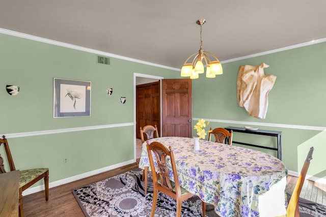 dining room featuring wood finished floors, visible vents, baseboards, ornamental molding, and an inviting chandelier