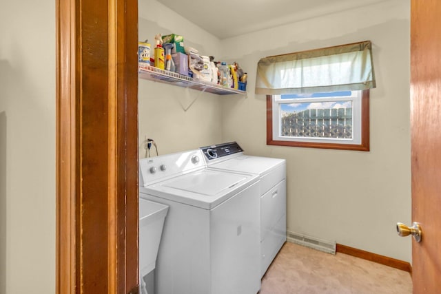 washroom featuring washing machine and dryer, laundry area, a sink, visible vents, and baseboards