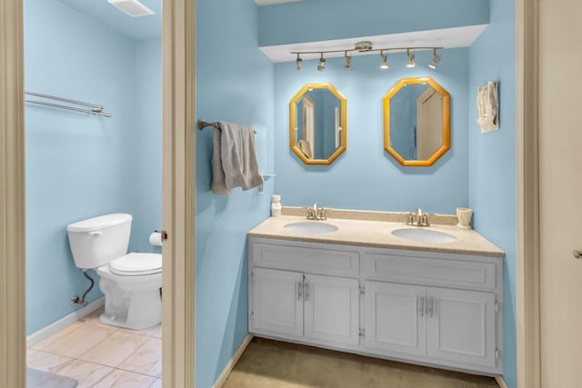 full bath featuring double vanity, a sink, toilet, and baseboards