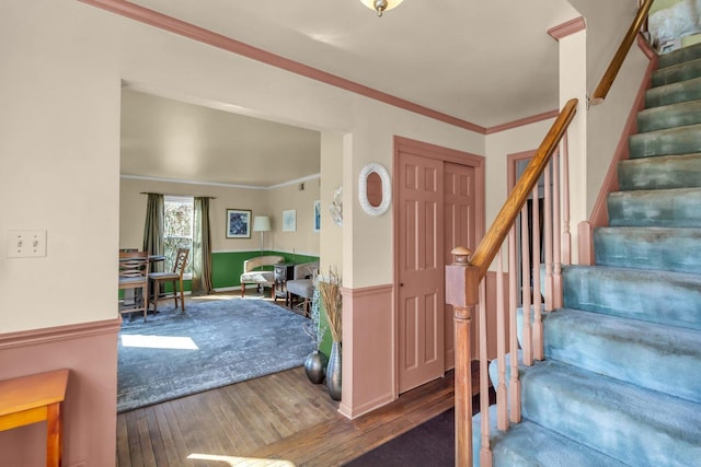 entrance foyer with stairs, a wainscoted wall, hardwood / wood-style flooring, and crown molding