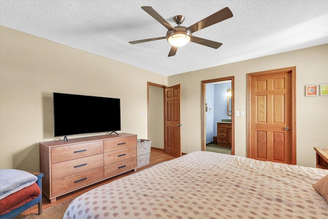 bedroom featuring ceiling fan, a textured ceiling, ensuite bath, and light wood finished floors