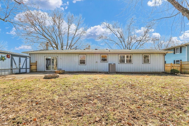 back of house featuring a storage unit, a lawn, fence, cooling unit, and an outdoor structure