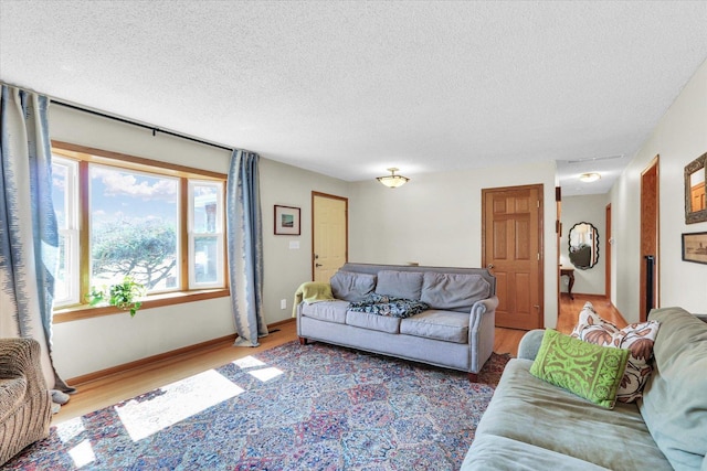 living area featuring light wood-style flooring, baseboards, and a textured ceiling