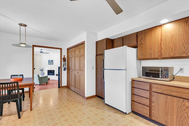 kitchen with stainless steel microwave, ceiling fan, light floors, light countertops, and freestanding refrigerator