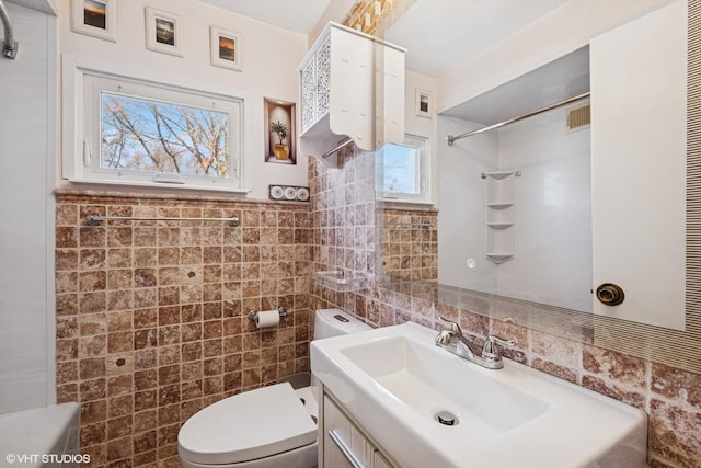 bathroom featuring vanity, tile walls, toilet, and visible vents