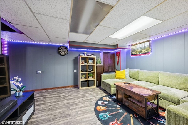 living area with a paneled ceiling and wood finished floors