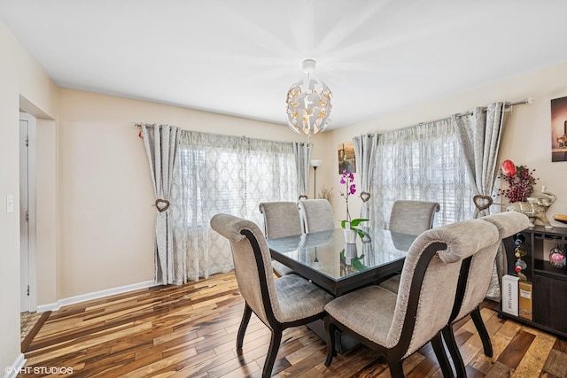 dining space featuring a notable chandelier, baseboards, and wood finished floors