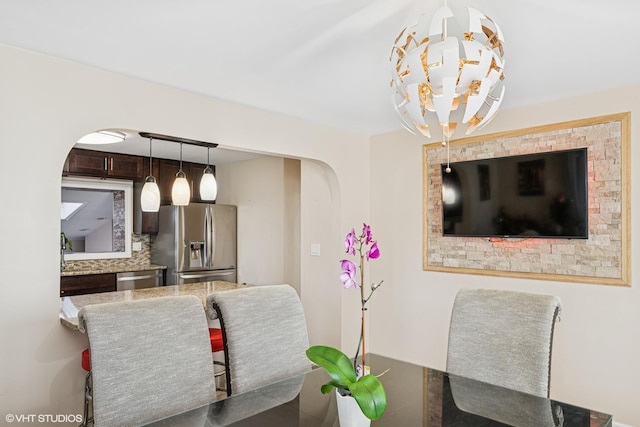 dining room with arched walkways and a chandelier