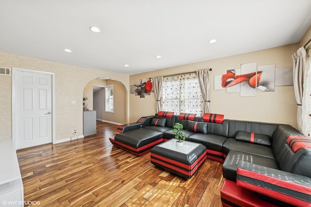 living area featuring visible vents, wood finished floors, recessed lighting, arched walkways, and baseboards