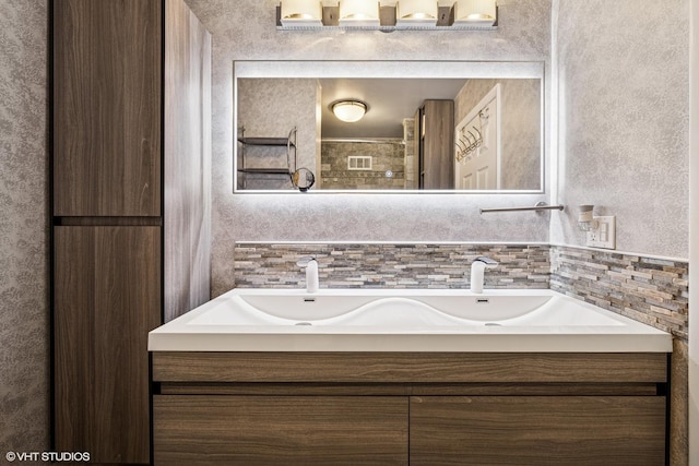 full bathroom featuring visible vents, walk in shower, decorative backsplash, and double vanity