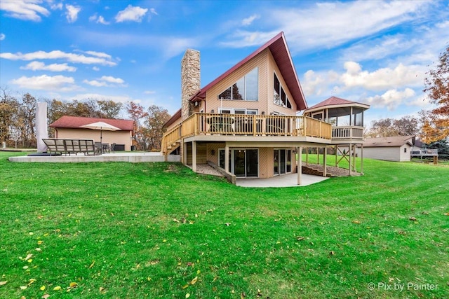 back of house featuring a chimney, a patio area, a lawn, and a wooden deck