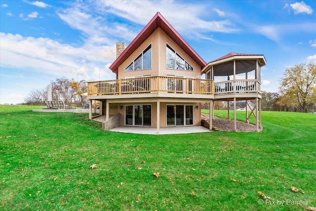 rear view of house with a wooden deck, a lawn, a chimney, a sunroom, and a patio