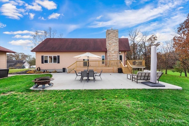 back of property with a fire pit, a wooden deck, a chimney, a yard, and a patio