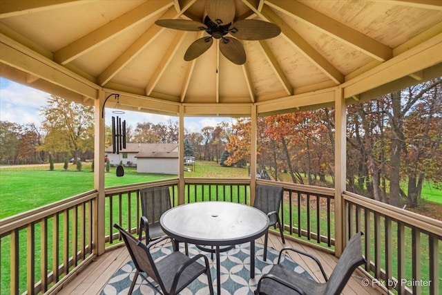 wooden deck featuring a gazebo, ceiling fan, outdoor dining area, and a yard