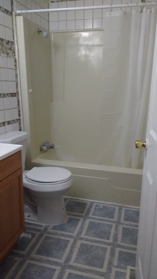 full bathroom with shower / bath combo, vanity, toilet, and tile patterned floors