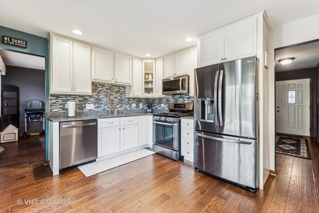 kitchen featuring backsplash, dark wood-style flooring, stainless steel appliances, and a sink