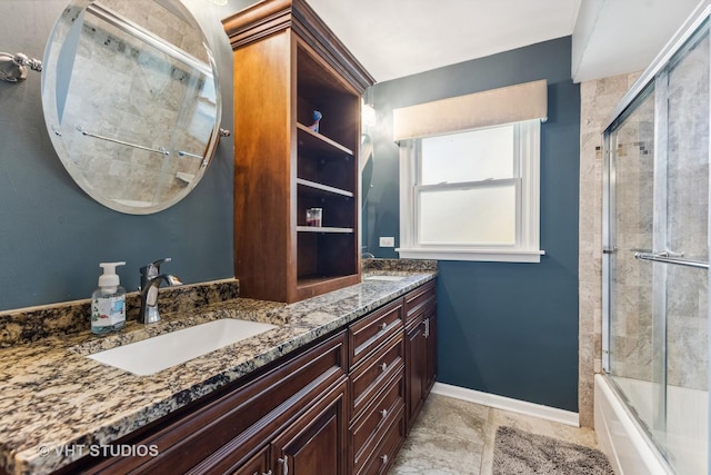 bathroom featuring enclosed tub / shower combo, double vanity, a sink, and baseboards