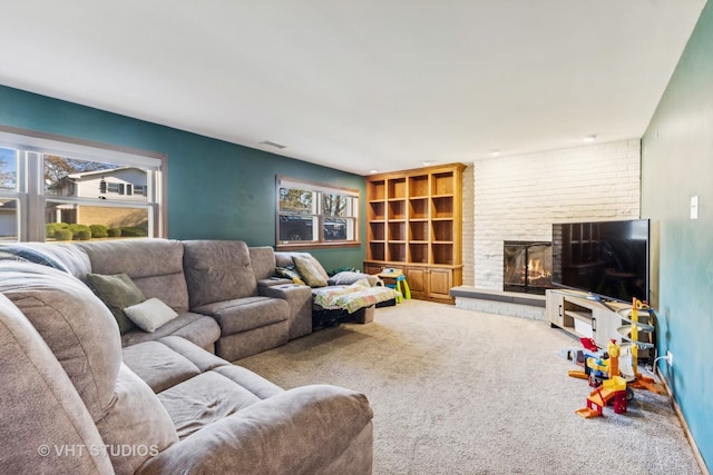 living room with a brick fireplace, carpet, and visible vents