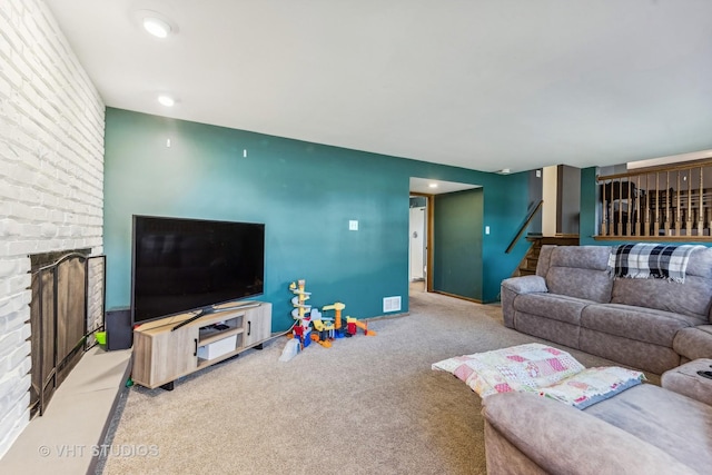 living room with a brick fireplace, stairway, and carpet flooring