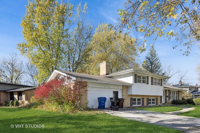 tri-level home featuring driveway, an attached garage, a front lawn, and brick siding