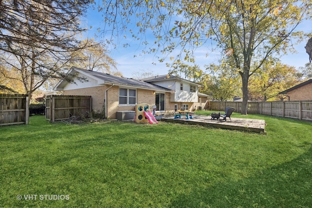 rear view of property with a yard, brick siding, a patio, and a fenced backyard