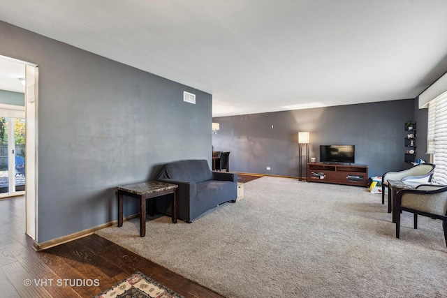 living room featuring visible vents, baseboards, and wood finished floors