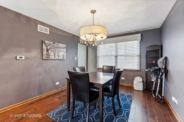 dining room with visible vents, a notable chandelier, baseboards, and hardwood / wood-style flooring