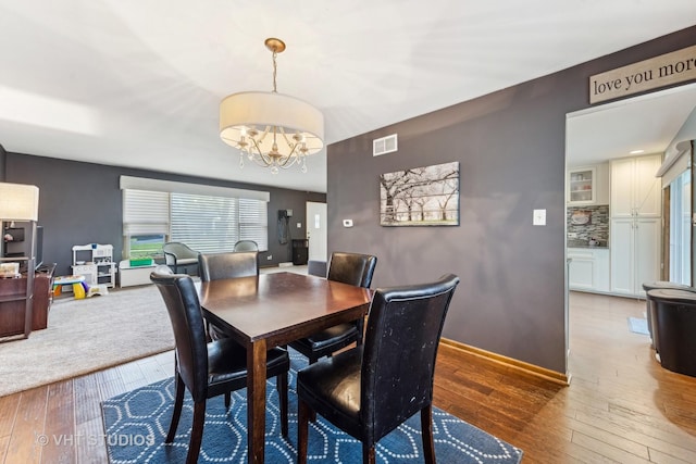 dining space featuring baseboards, a notable chandelier, visible vents, and hardwood / wood-style floors