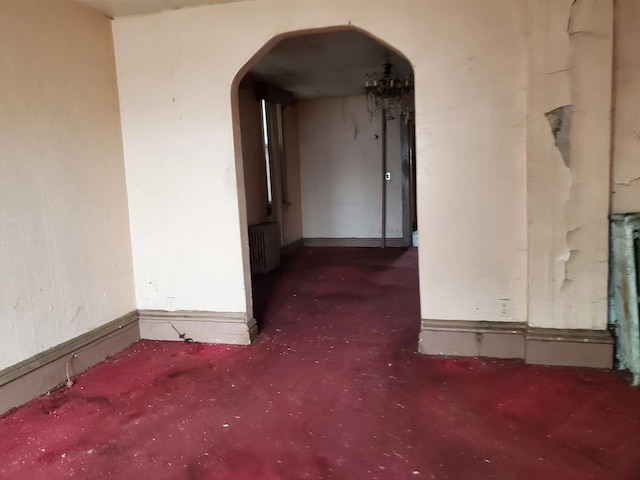 empty room with radiator heating unit, arched walkways, and baseboards