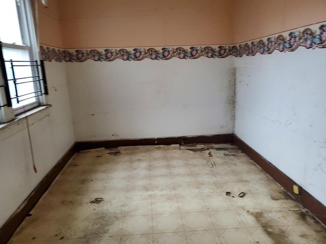 spare room featuring light floors and baseboards