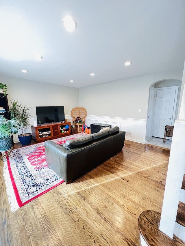 living room featuring a wainscoted wall, arched walkways, wood finished floors, and recessed lighting