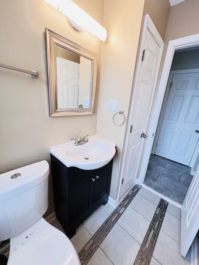 half bath with toilet, vanity, baseboards, and tile patterned floors