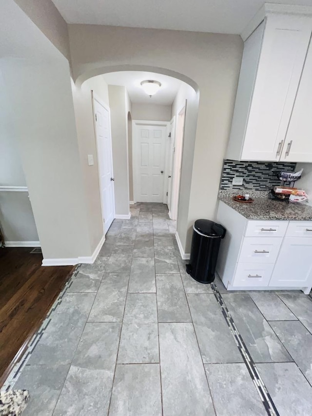 corridor featuring arched walkways and baseboards