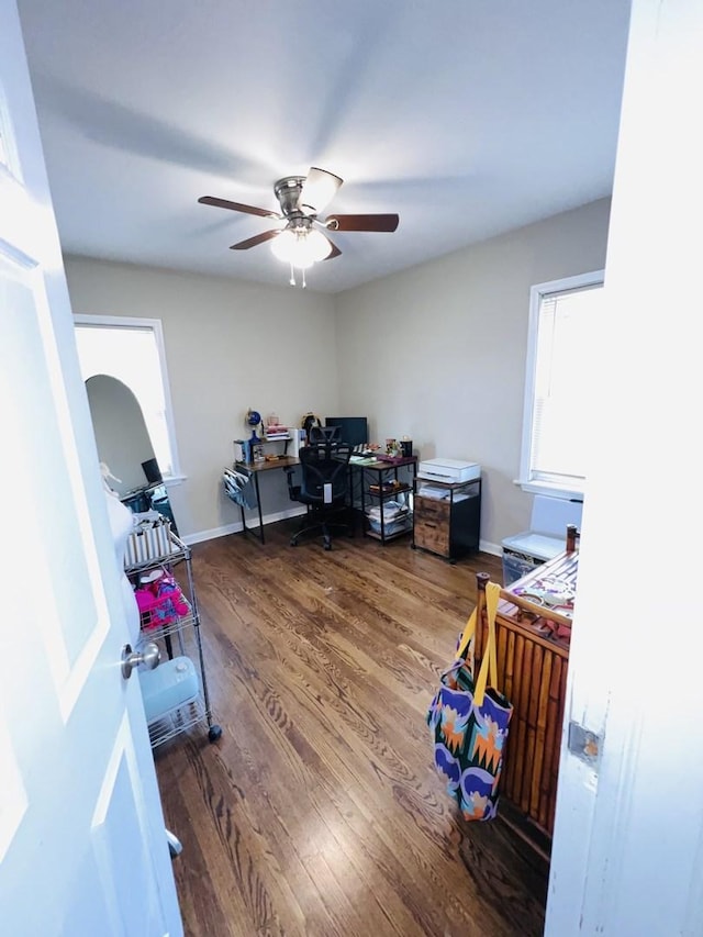 office area featuring arched walkways, wood finished floors, a ceiling fan, and baseboards