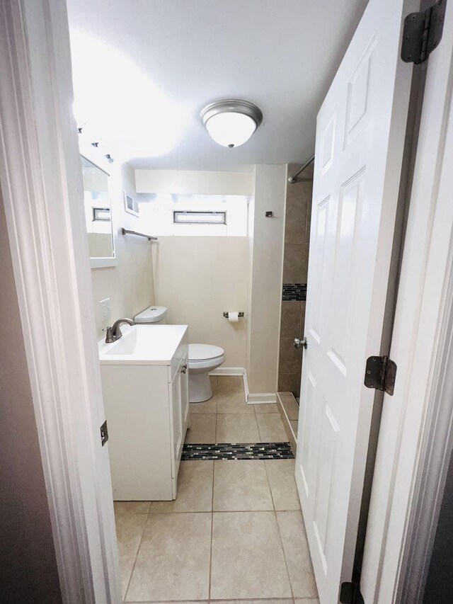 bathroom with visible vents, toilet, a tile shower, vanity, and tile patterned floors