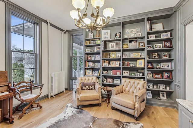 living area with a chandelier, light wood-type flooring, and radiator