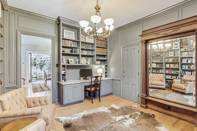 office area featuring light wood finished floors, a chandelier, built in features, and built in study area