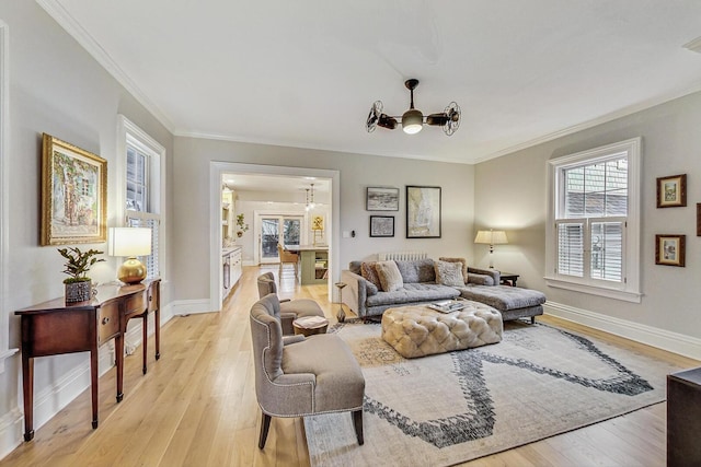 living area with crown molding, light wood-type flooring, a notable chandelier, and baseboards