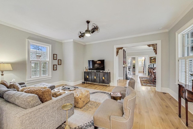 living room with light wood-type flooring, baseboards, and ornamental molding