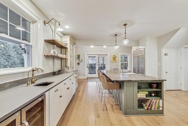 kitchen with wine cooler, stainless steel built in fridge, a sink, and open shelves