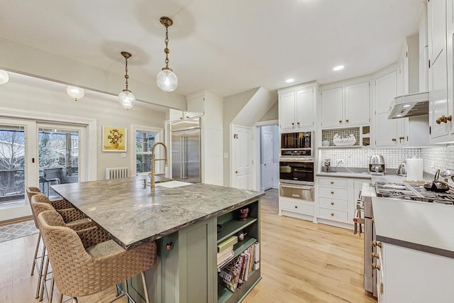 kitchen with white cabinetry, open shelves, light wood finished floors, and built in appliances