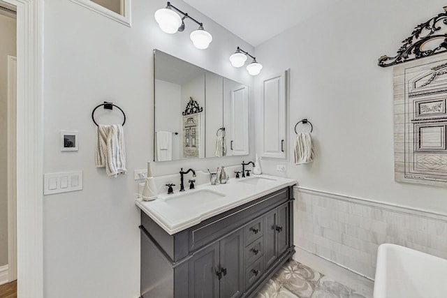 full bathroom featuring a wainscoted wall, a sink, tile walls, and double vanity