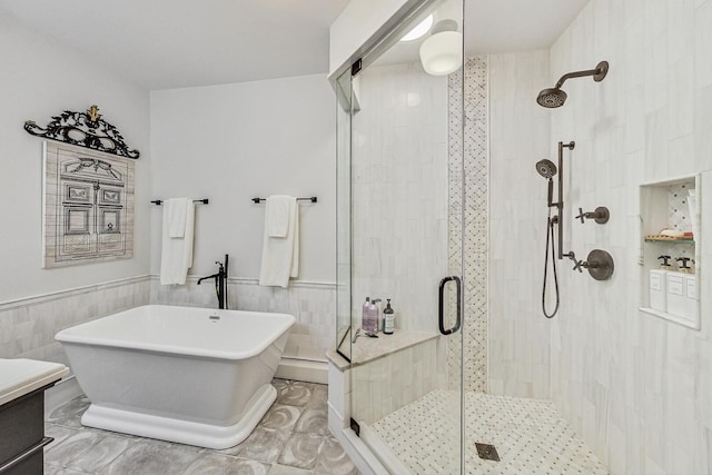 full bath featuring tile walls, a wainscoted wall, and a shower stall