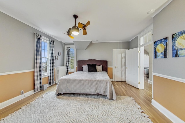 bedroom with baseboards, ceiling fan, ornamental molding, and light wood-style floors