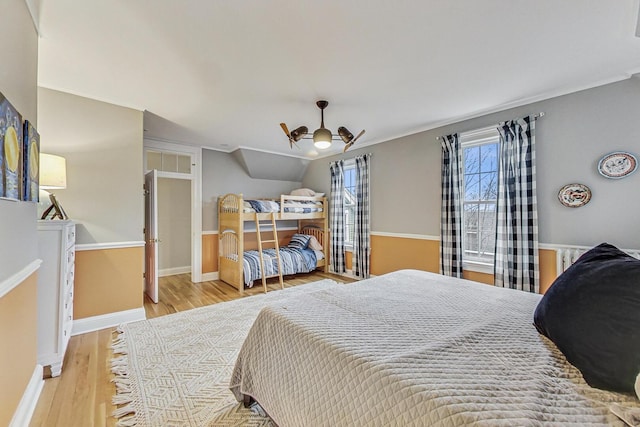 bedroom featuring lofted ceiling, baseboards, and wood finished floors