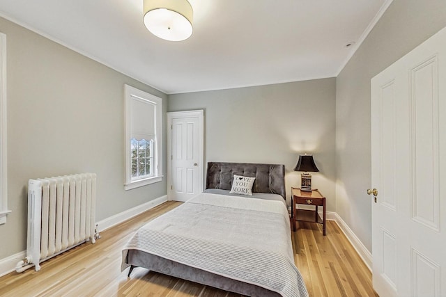 bedroom with radiator, light wood-style flooring, and baseboards